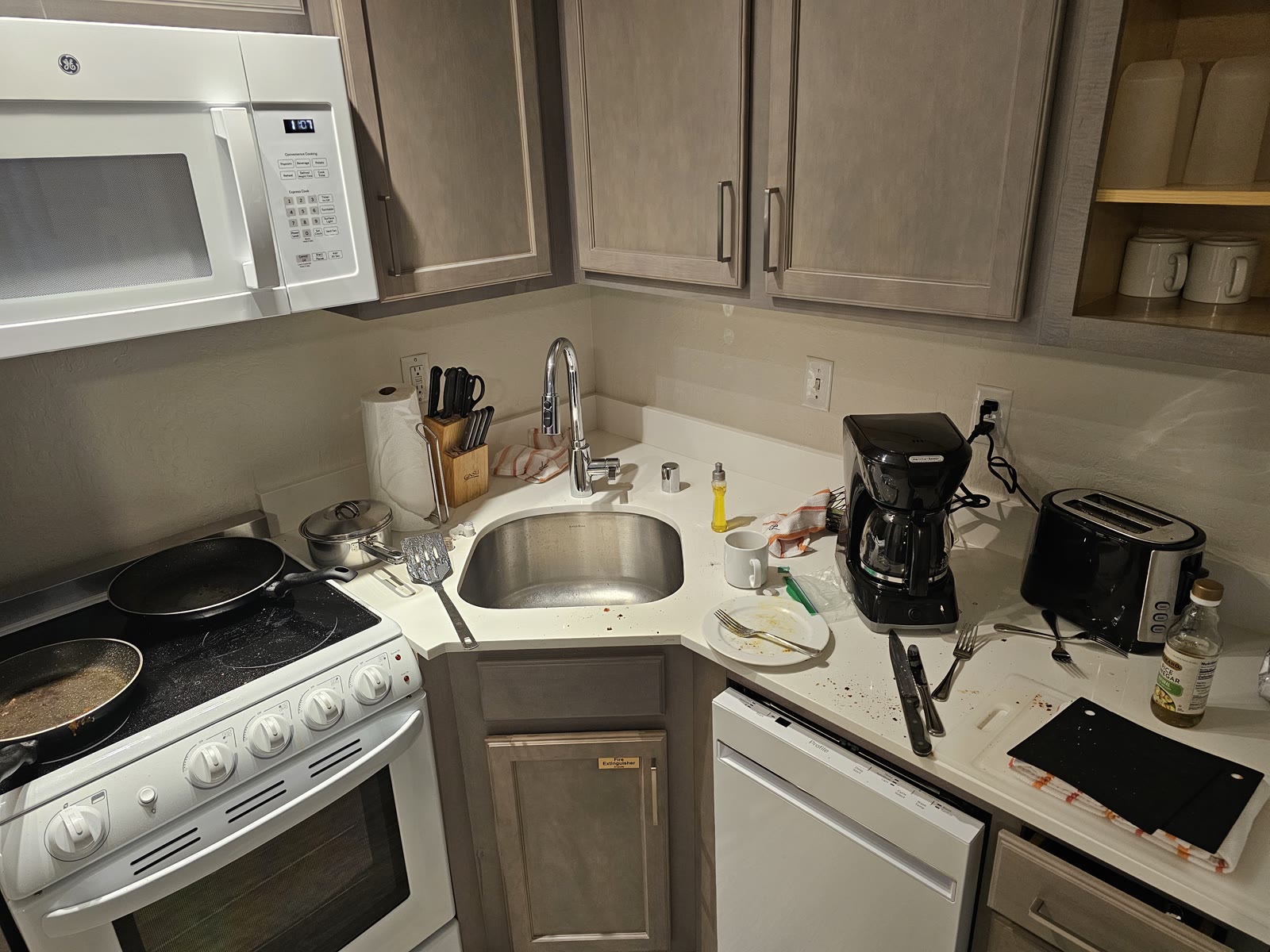 The kitchen before cleaning: pans on the stove, dirty dishes and crumbs on the counter