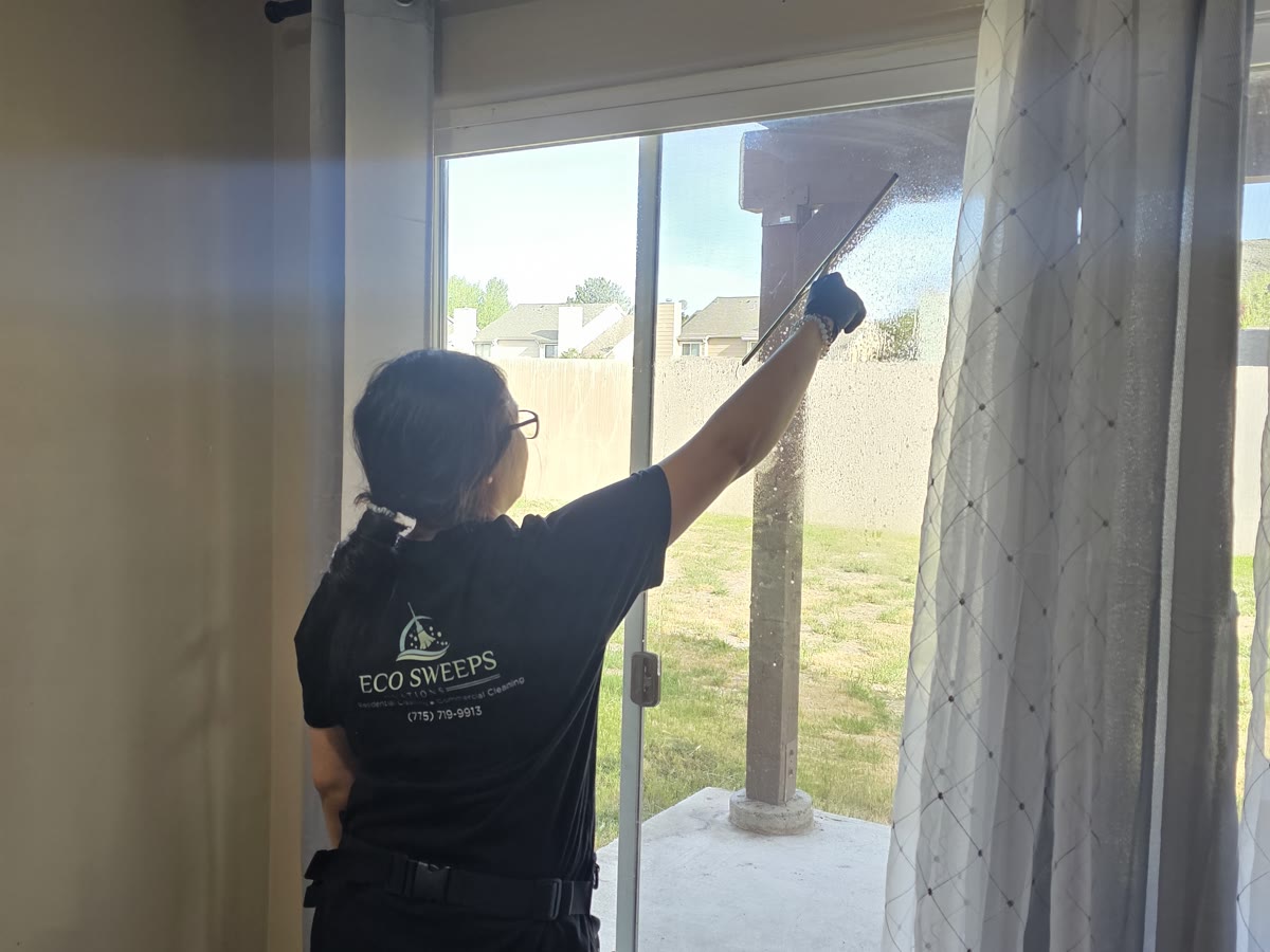 An Eco Sweeps cleaner squeegeeing a large glass door